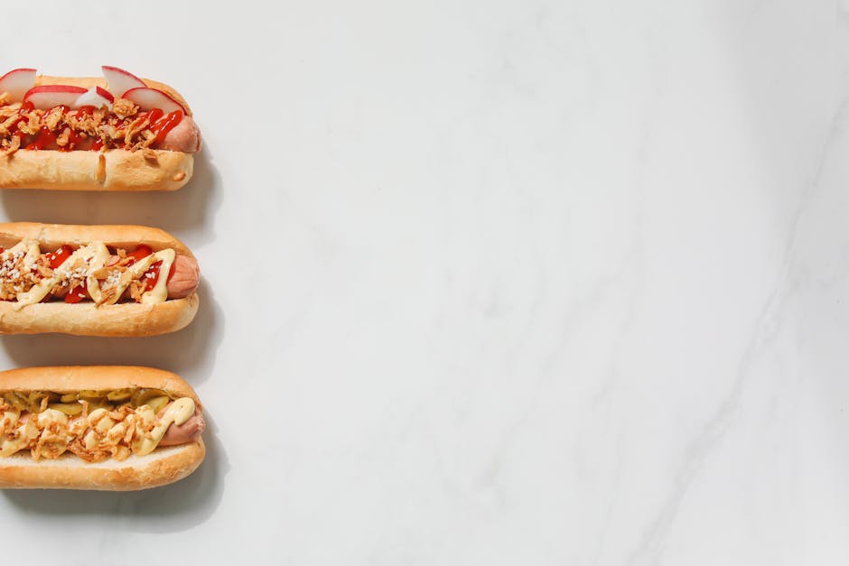 Three gourmet hot dogs with various toppings on a marble background