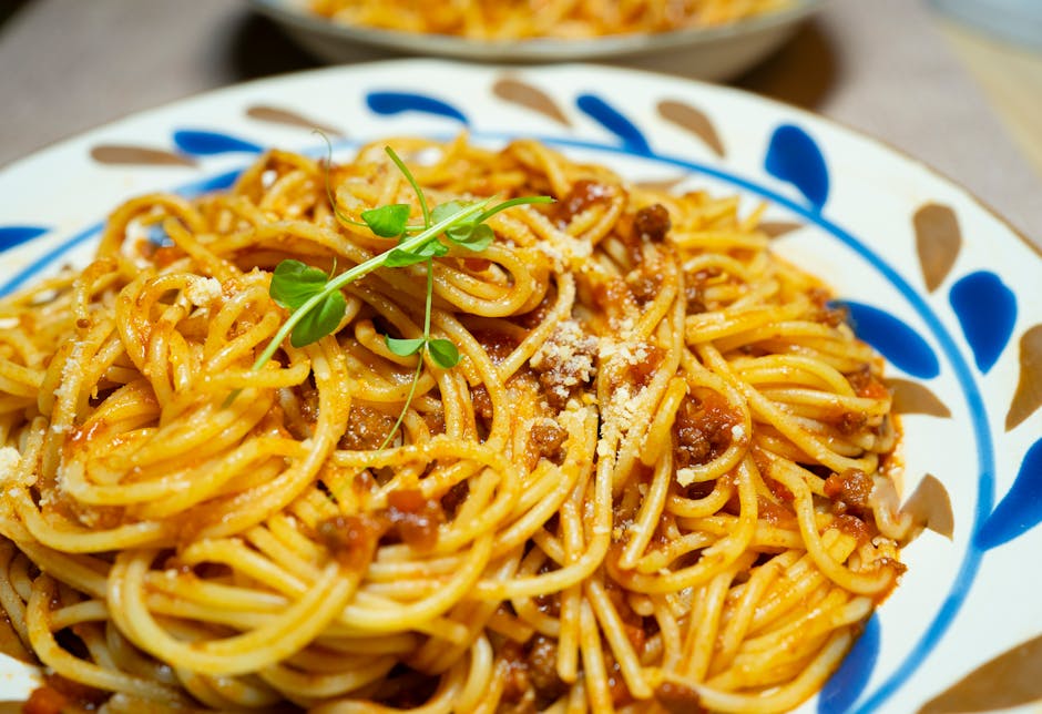 Close-up of savory spaghetti Bolognese garnished with fresh herbs on a decorative plate
