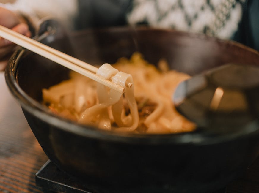 Close-up of steaming udon noodles in a bowl with chopsticks, perfect for a cozy meal